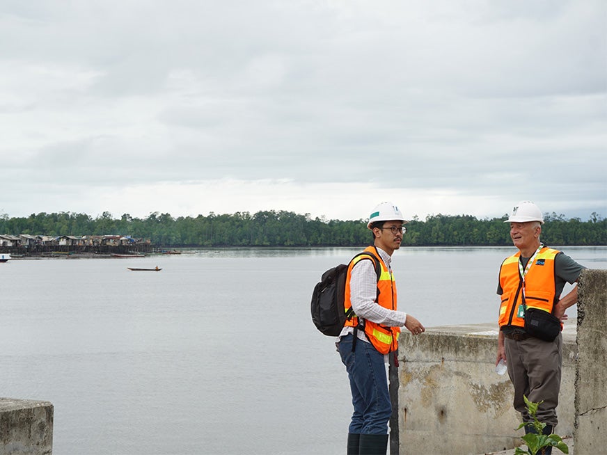 Two people in construction vests standing in front of a lake