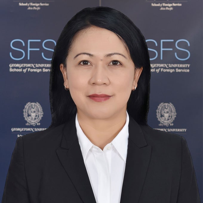 Portrait of Elis Nurhayati in a suit standing in front of an SFS backdrop.