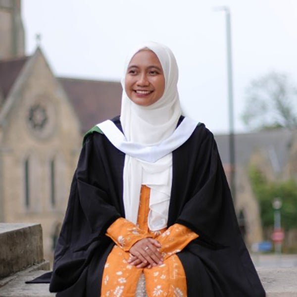 Mega Puspita wearing a kerchief, standing in front of a cathedral