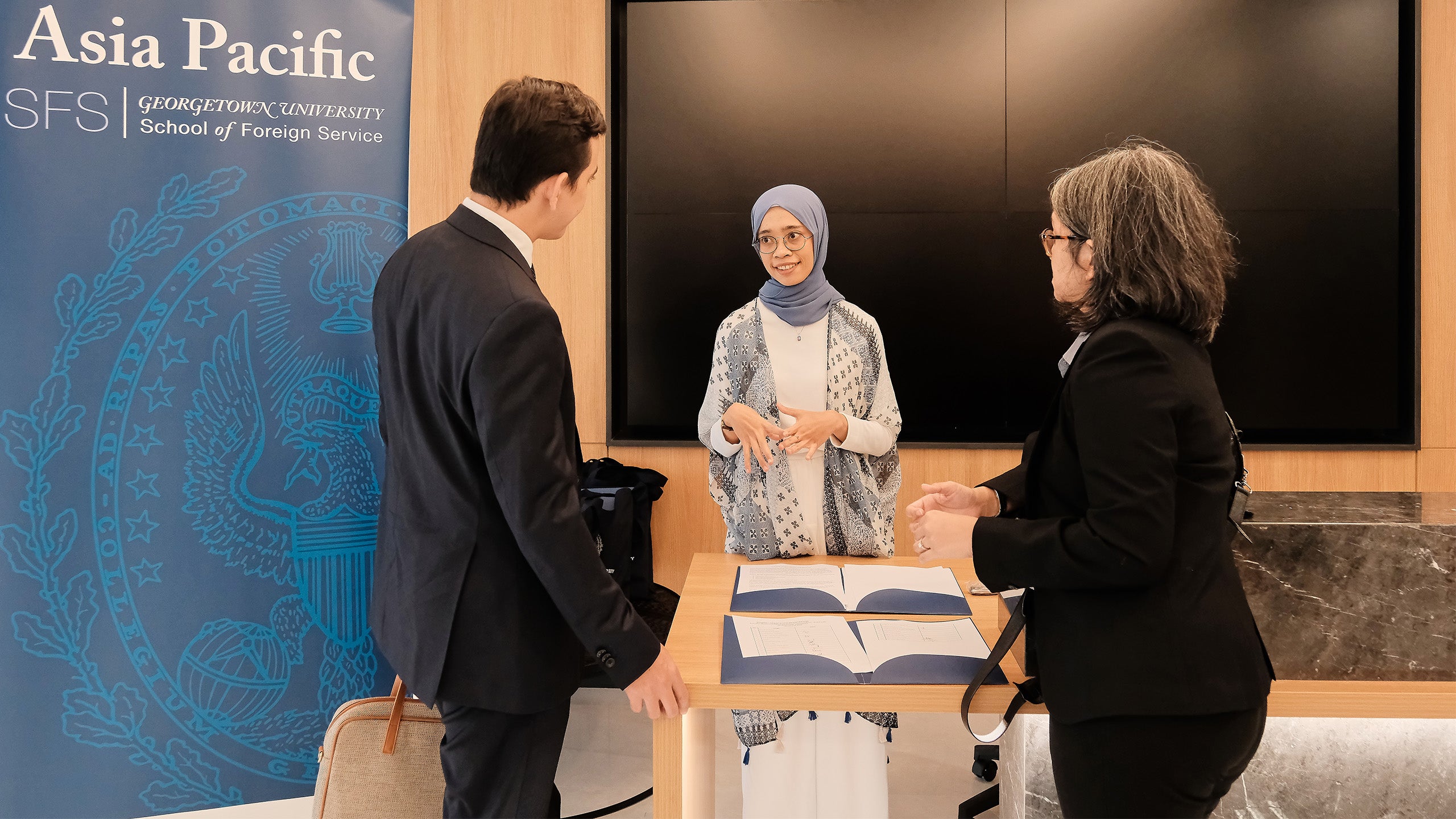 A woman wearing a headscarf talking to other guests