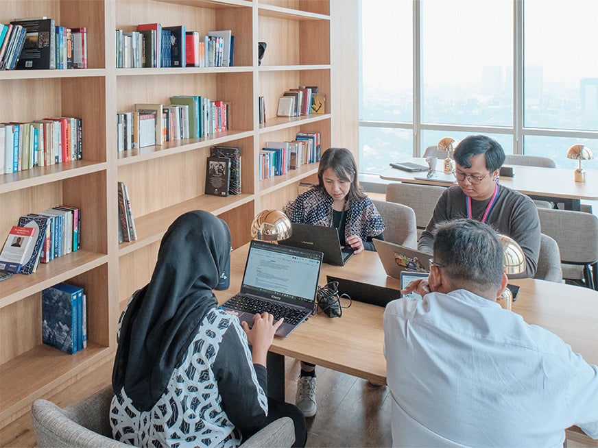 Students studying in a room with bookshelves behind them.