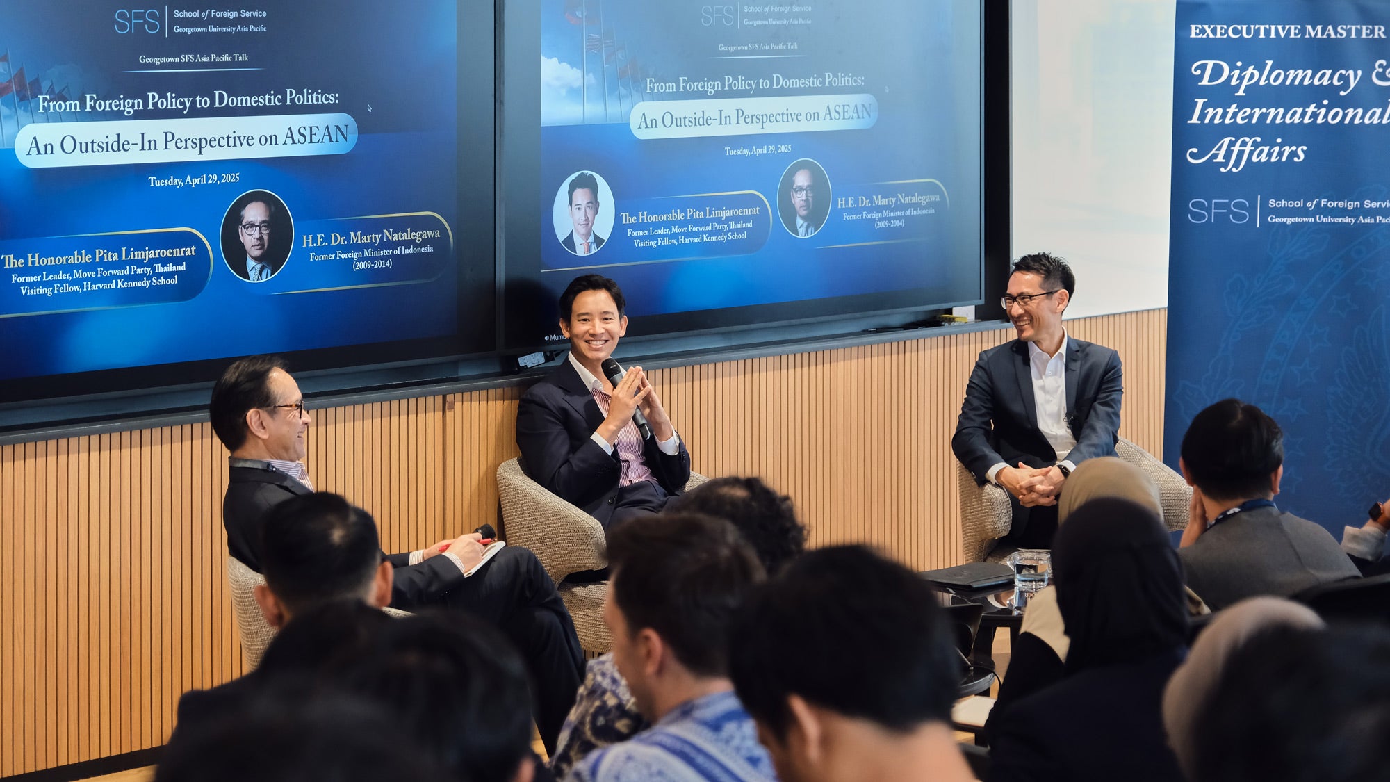 Three speakers giving a panel in front of a classroom