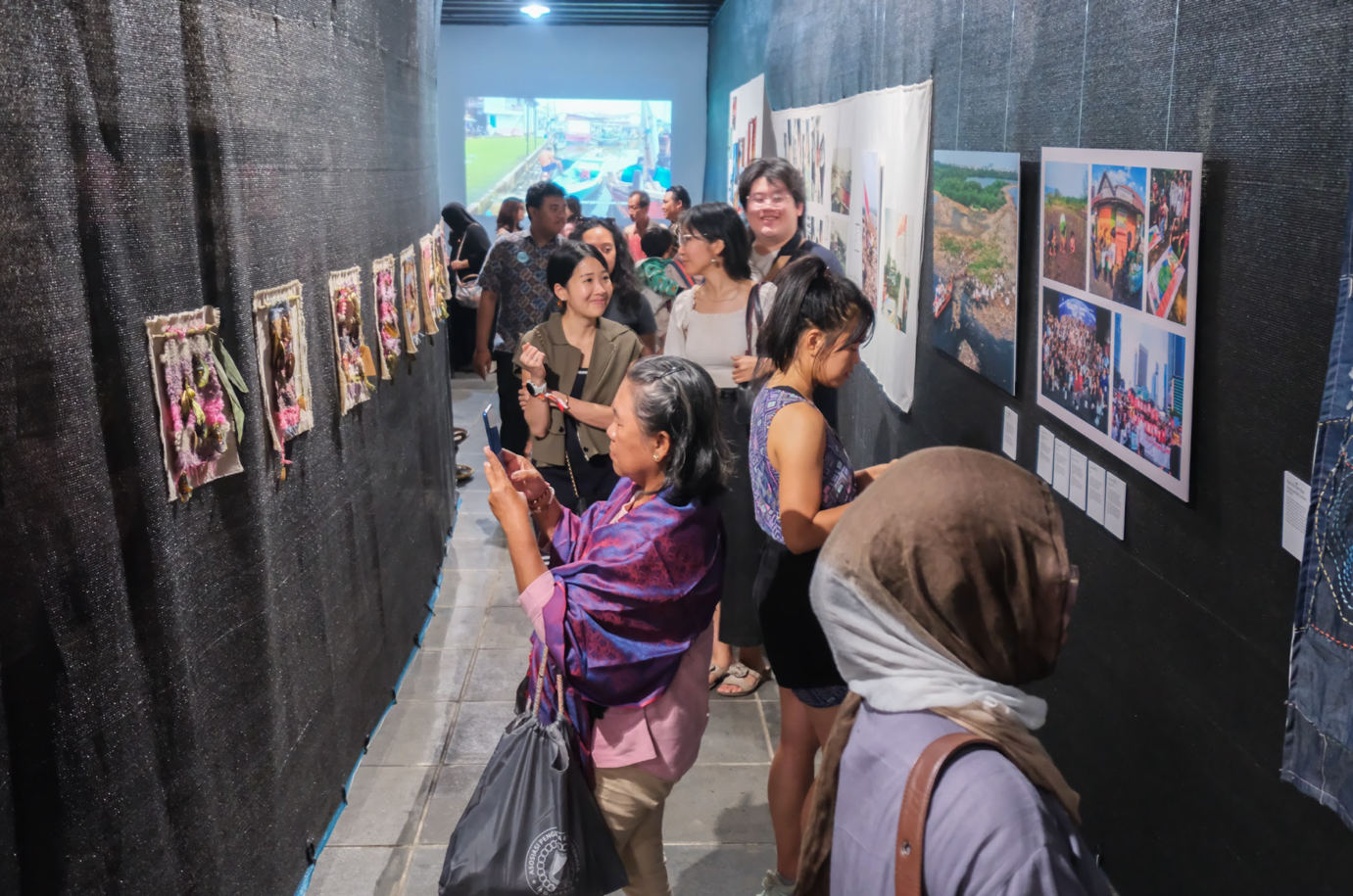 Visitors exploring textile and photographic works at an exhibition by Women of Muara Angke and collaborators.