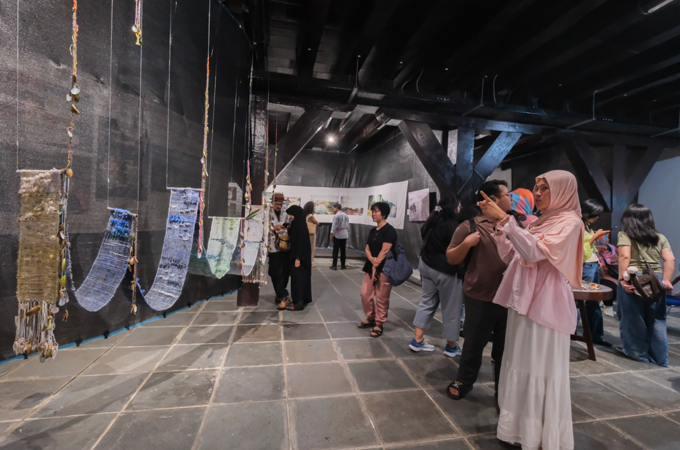 Visitors viewing photographs and mixed-media artworks at the exhibition.